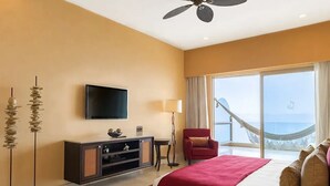 Una habitación de hotel con cama, televisión, escritorio, silla y vista al océano.