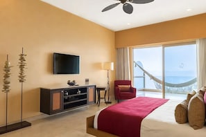 Ein Hotelzimmer mit Bett, Fernseher, Schreibtisch, Stuhl und Meerblick.