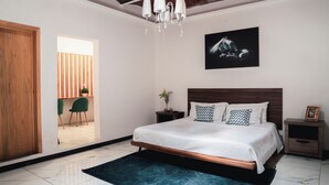 Une chambre à coucher comprenant un lit, des tables de chevet, un lustre, un tableau et une vue sur un espace extérieur.
