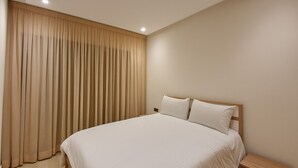 A bedroom with a large bed, a wooden nightstand, and beige curtains. - Cosy Apparts 2BR in downtown (Casablanca)