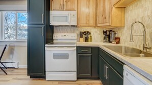 A kitchen with a microwave, stove, sink, and wooden cabinets.