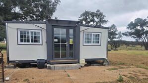 A small, single-story mobile home with a front door and two windows on the side.