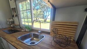 A kitchen with a wooden countertop, stainless steel sink, and a window with a view of greenery.