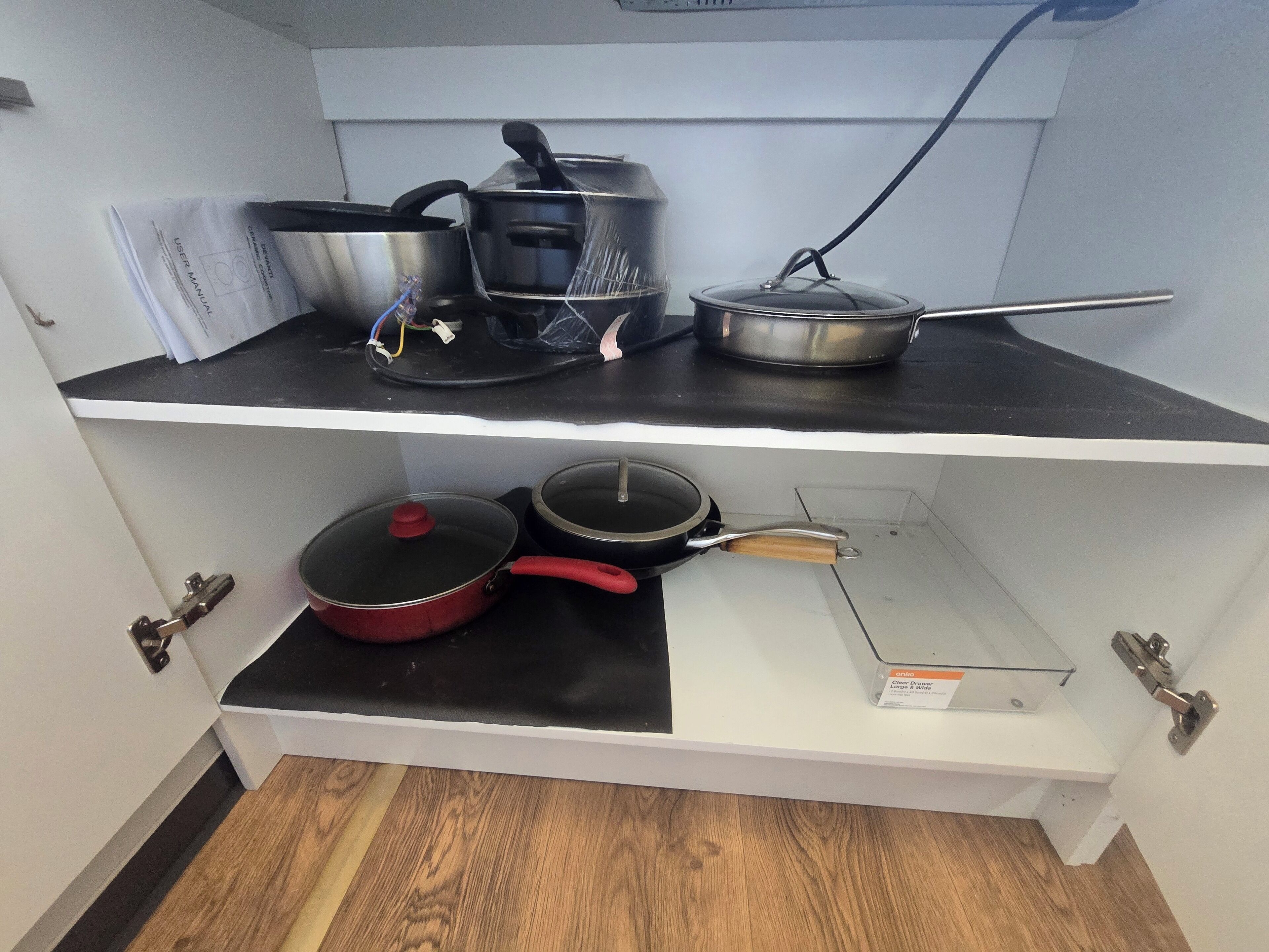 A kitchen with two shelves, containing various pots and pans.