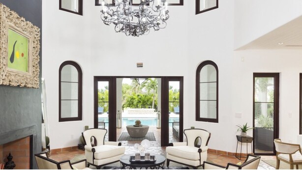 A spacious living room with a fireplace, a chandelier, and a view of a pool. - World Cup 2026 Dream Villa 3 (Miami)