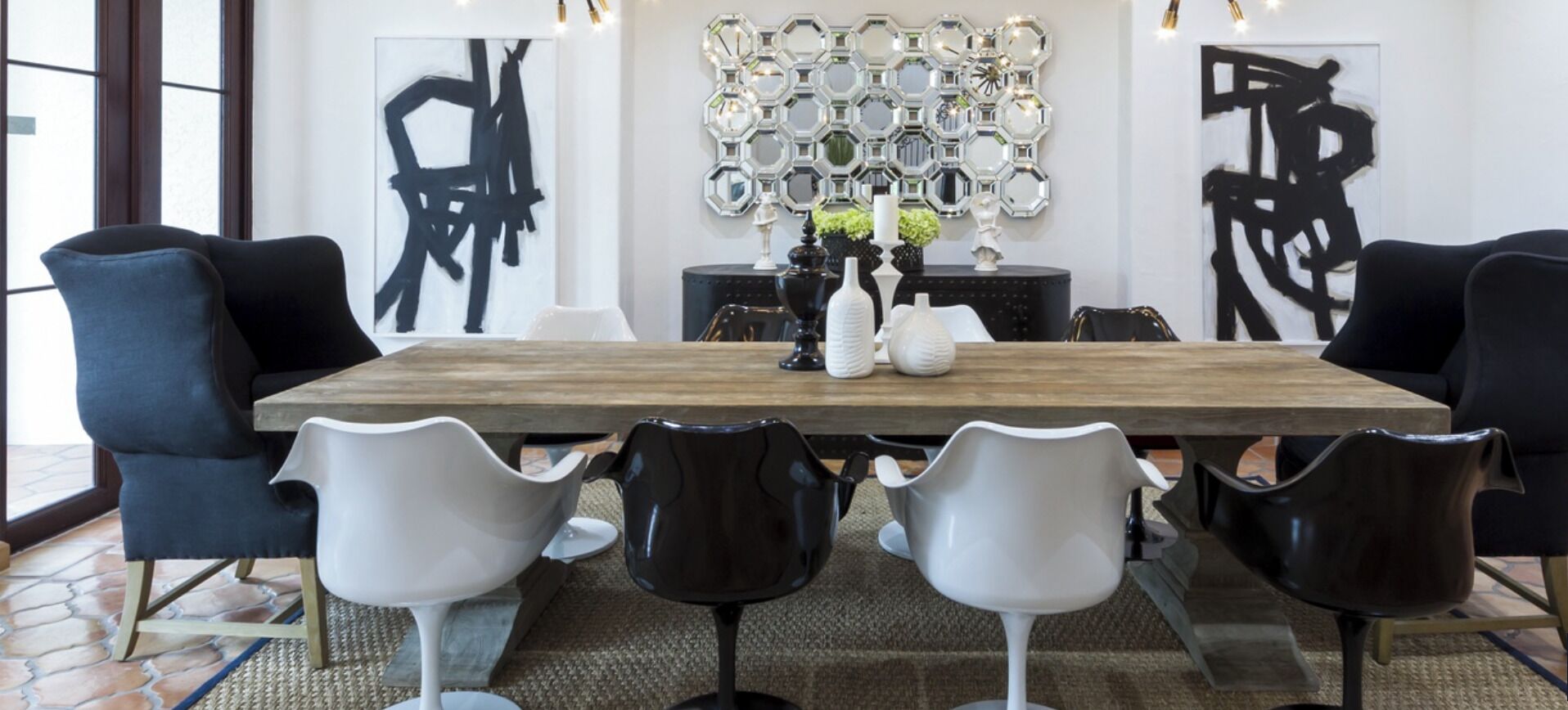 A dining area with a wooden table, black and white chairs, and abstract art on the walls.