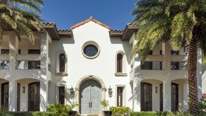 A multi-story building with a symmetrical facade, arched windows, and a central circular window. - World Cup 2026 Dream Villa 3 (Miami)