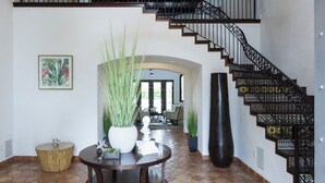 A foyer with a staircase, a round table with plants, a large vase, and a framed picture on the wall. - World Cup 2026 Dream Villa 3 (Miami)