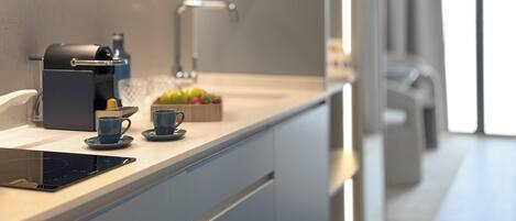 Une cuisine moderne équipée d’une machine à café intégrée, d’une bouilloire et d’un panier à fruits.