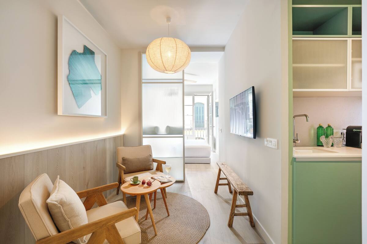 Ein modernes Wohnzimmer mit einer Couch, Sesseln, einem kleinen Tisch und einer Pendelleuchte.