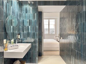 Un baño moderno con un lavamanos blanco, un espejo grande y baldosas azul oscuro.