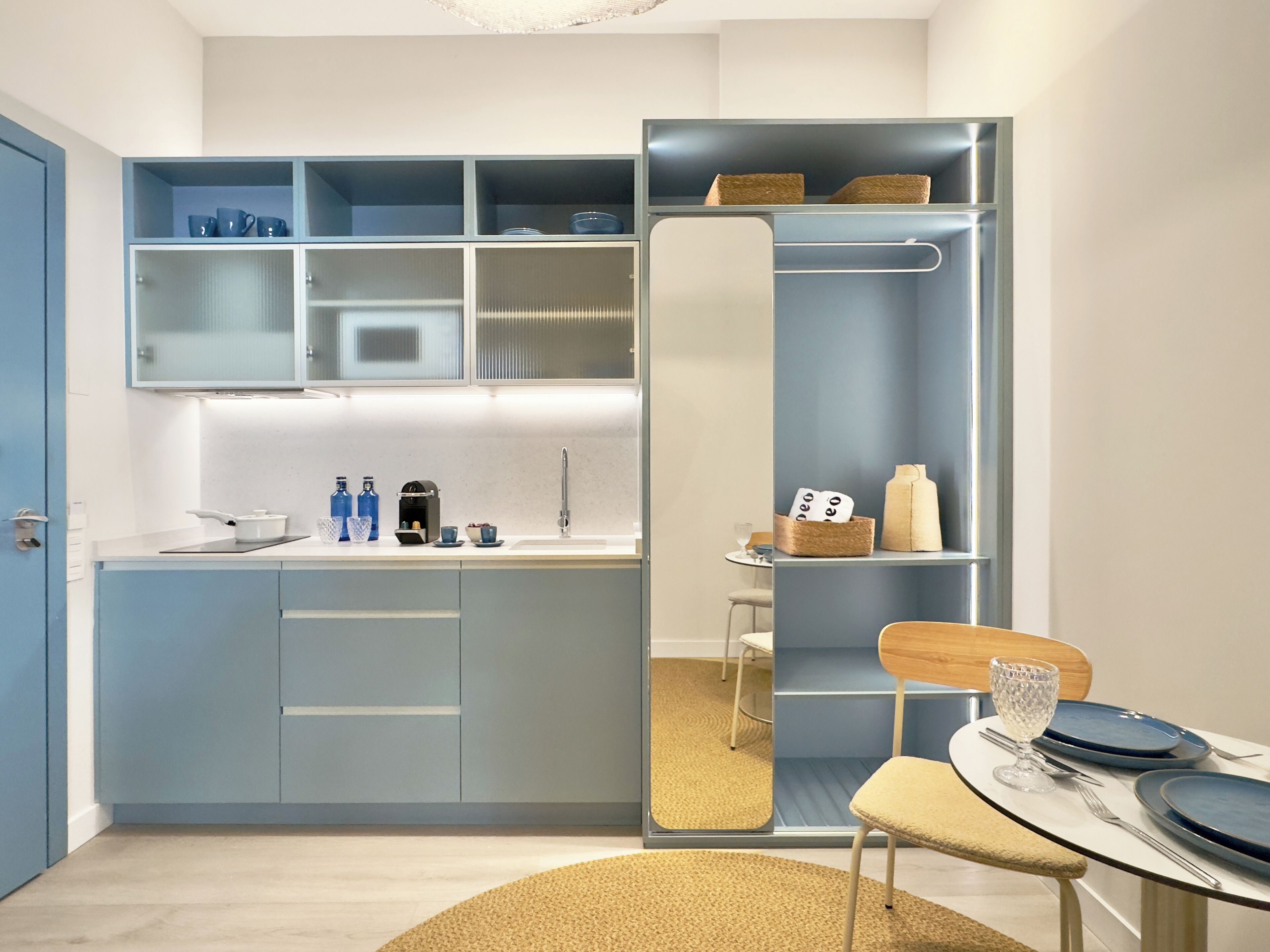 A modern kitchen with a built-in island, a dining area with a round table, and a mirrored closet door.