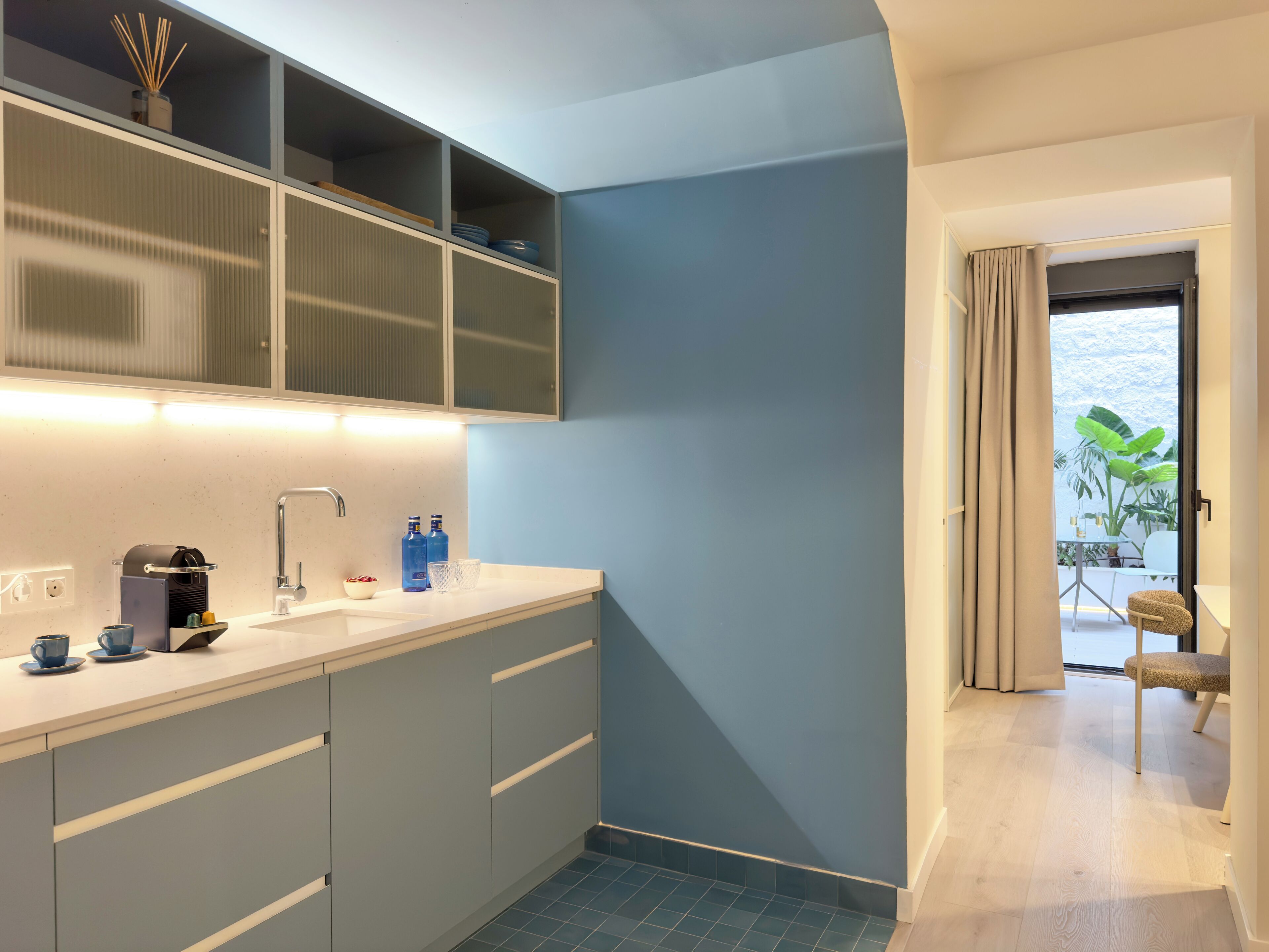 A modern kitchen with a sink, countertop, and cabinets. There is a window with a view of greenery outside.