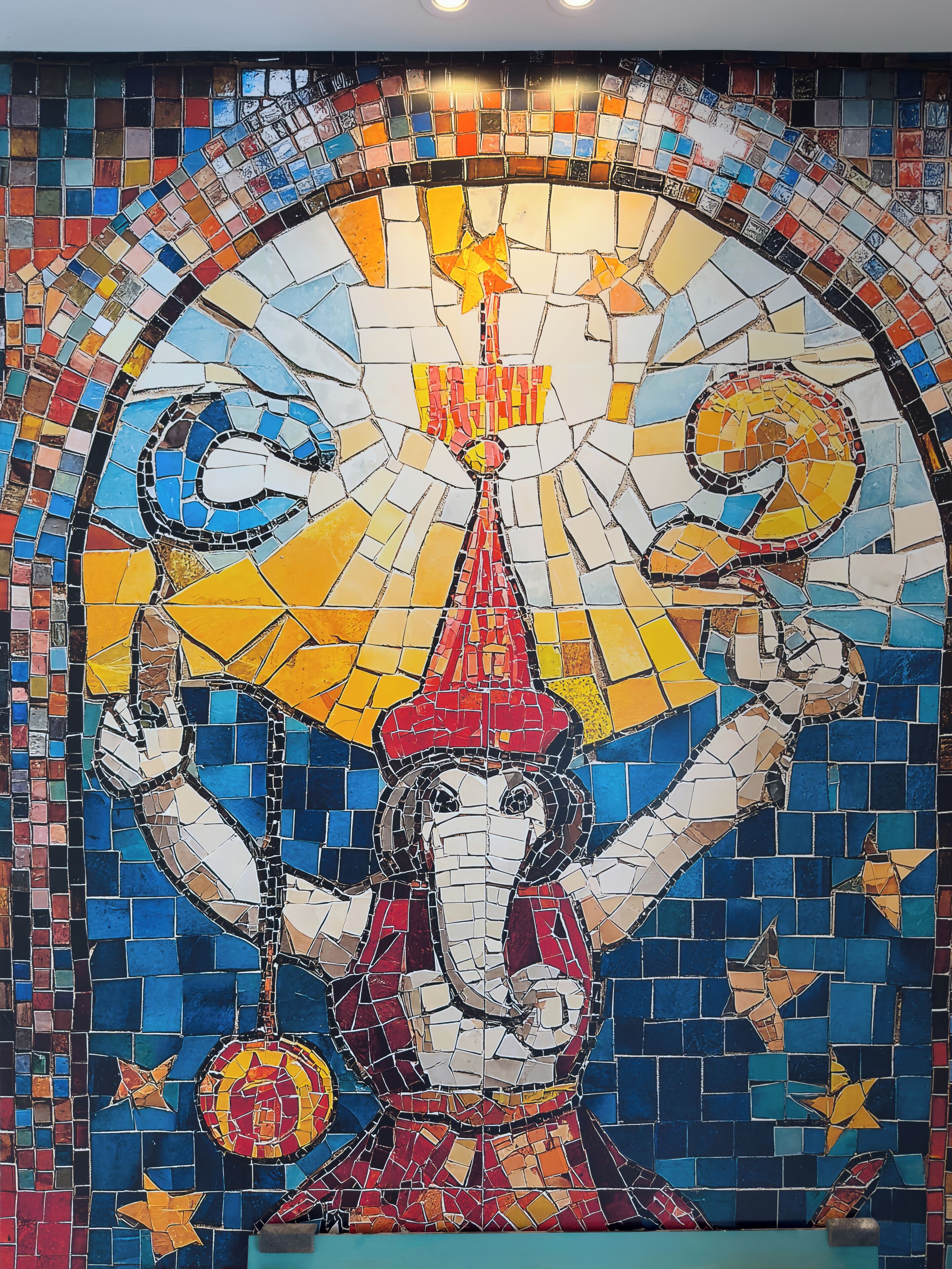 A mosaic of a figure with multiple arms, a headdress, and a central flame.