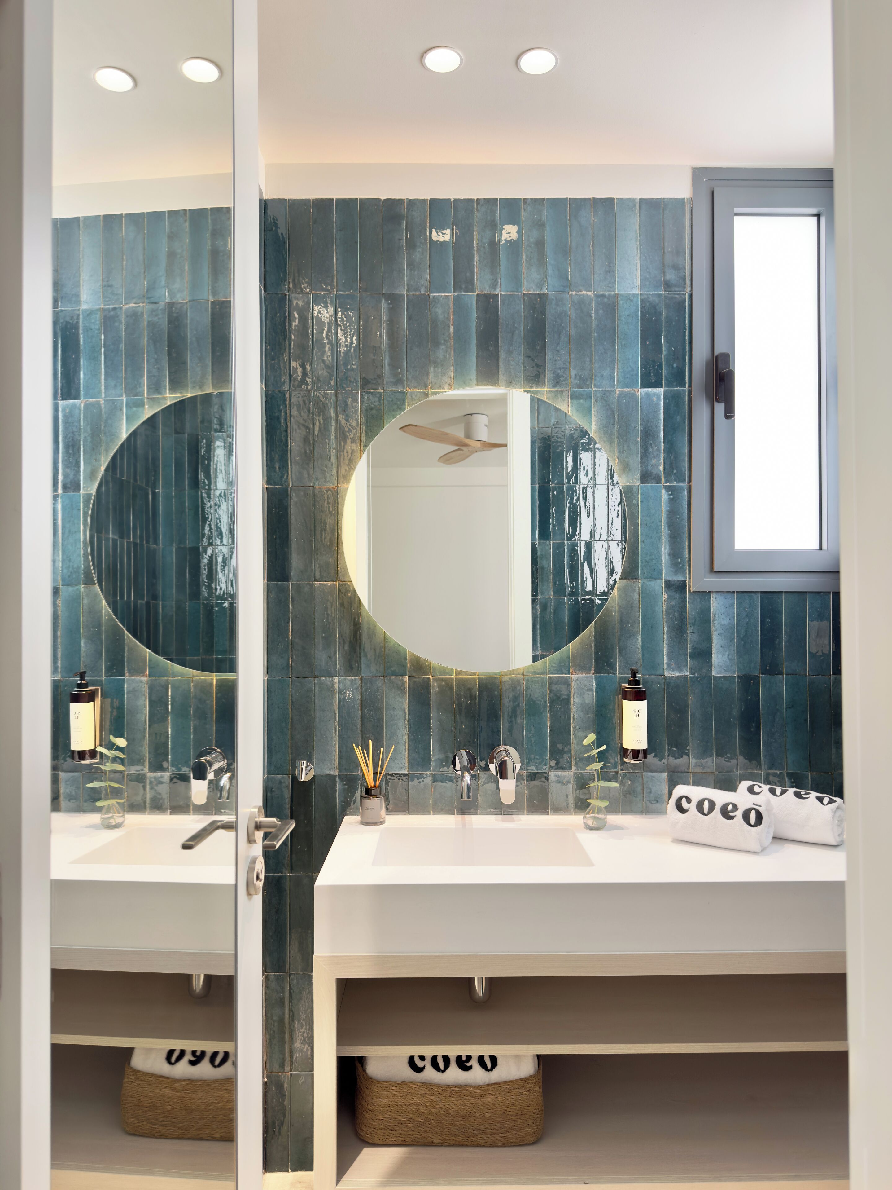 A bathroom with a white sink, two mirrors, and a ceiling fan.