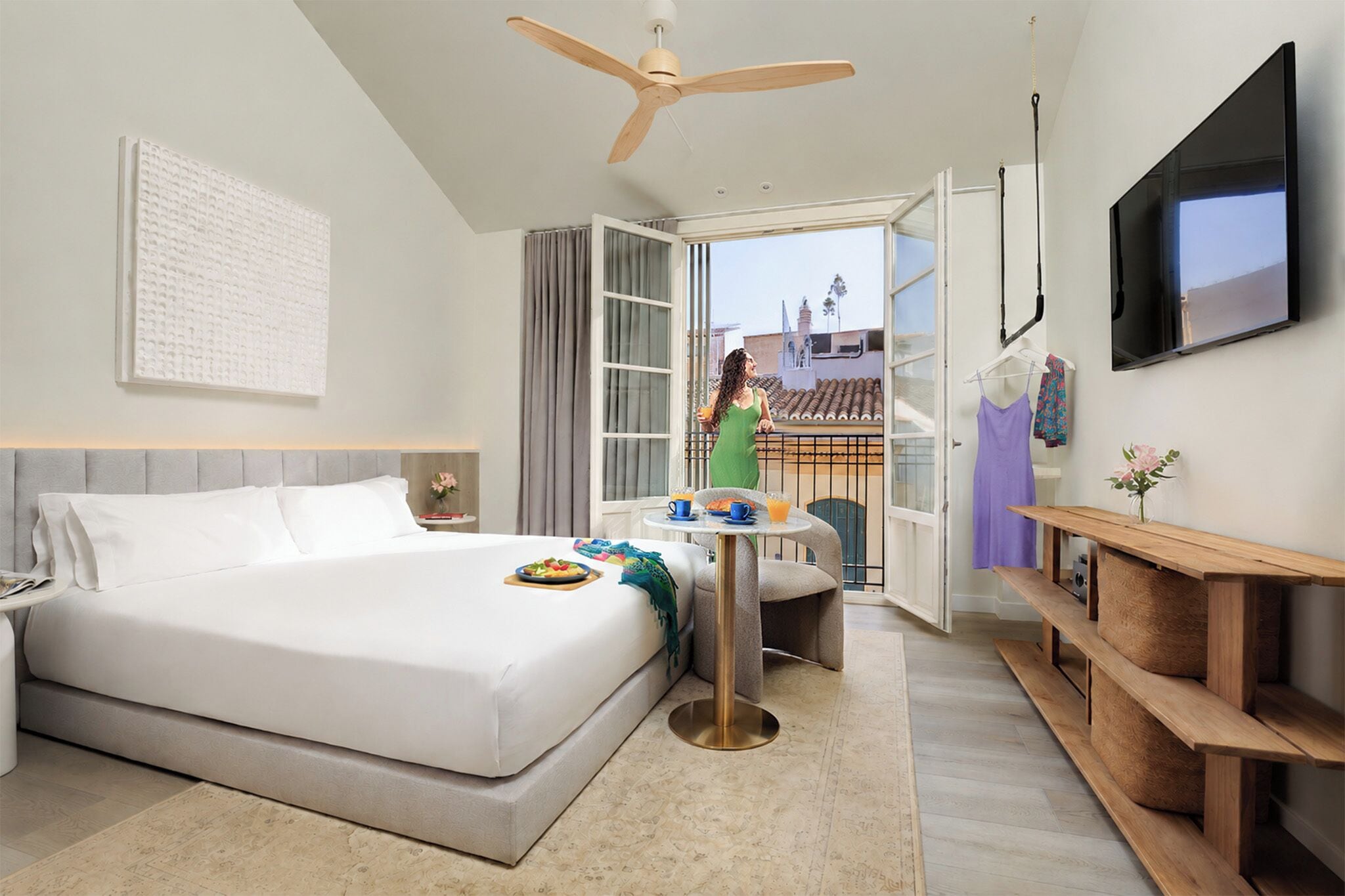 Habitación de hotel con cama, escritorio, televisión y balcón con vistas.