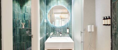 A modern bathroom with a white sink, a mirror, and a shower area.