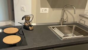 A modern kitchen with a built-in stove, a sink, and a coffee maker. - Loreto Suite 7 minutes from Duomo AC Wi Fi (Milano)