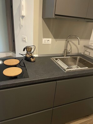 A modern kitchen with a built-in stove, a sink, and a coffee maker.