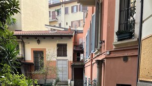 A narrow cobblestone courtyard with potted plants and a small staircase leading to a door. - Loreto Suite 7 minutes from Duomo AC Wi Fi (Milano)