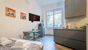 A compact hotel room with a bed, a desk, a TV, and a kitchenette. - Loreto Suite 7 minutes from Duomo AC Wi Fi (Milano)