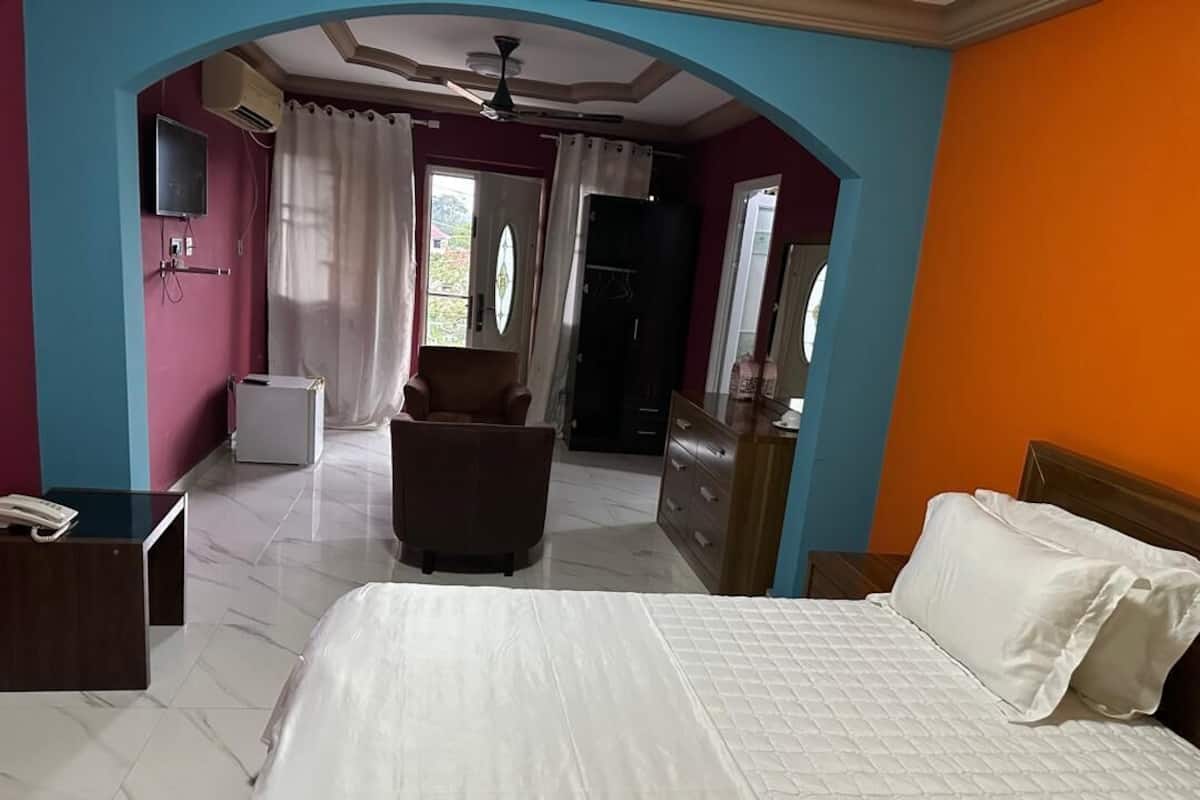 A hotel room with a bed, a desk, a chair, a wardrobe, and a bathroom.