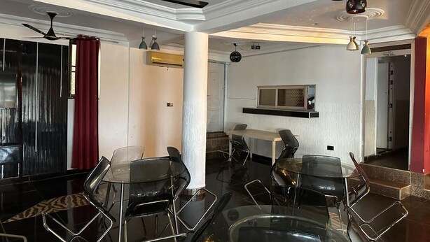 A modern dining area with a glass table and black chairs, a ceiling fan, and pendant lights. - GQ Luxury Hills Hotel- Akropong Akwapim (Akropong)