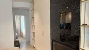 Une cuisine moderne avec un revêtement mural en marbre noir, un téléviseur encastré et un plancher en bois.