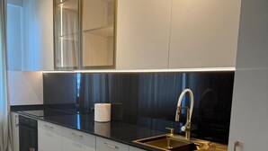 Une cuisine moderne avec un plan de travail noir, un évier en acier inoxydable et des armoires blanches.