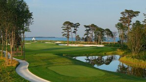 A golf course with a water hazard, sand bunkers, and a white gazebo in the distance. - Resort Retreat: King Suites & Nature Trails (Millsboro)