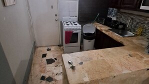 Una cocina con estufa a gas, un cubo de basura y una encimera.