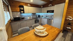 A modern kitchen with wooden accents, a dining table with a decorative centerpiece, and built-in appliances. - Madeira House (Starzach)