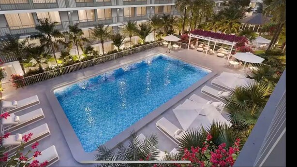 Una piscina sul tetto con vista su un edificio moderno, circondata da palme e lettini da relax.
