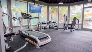 Una palestra con tapis roulant, manubri e attrezzature per esercizi.