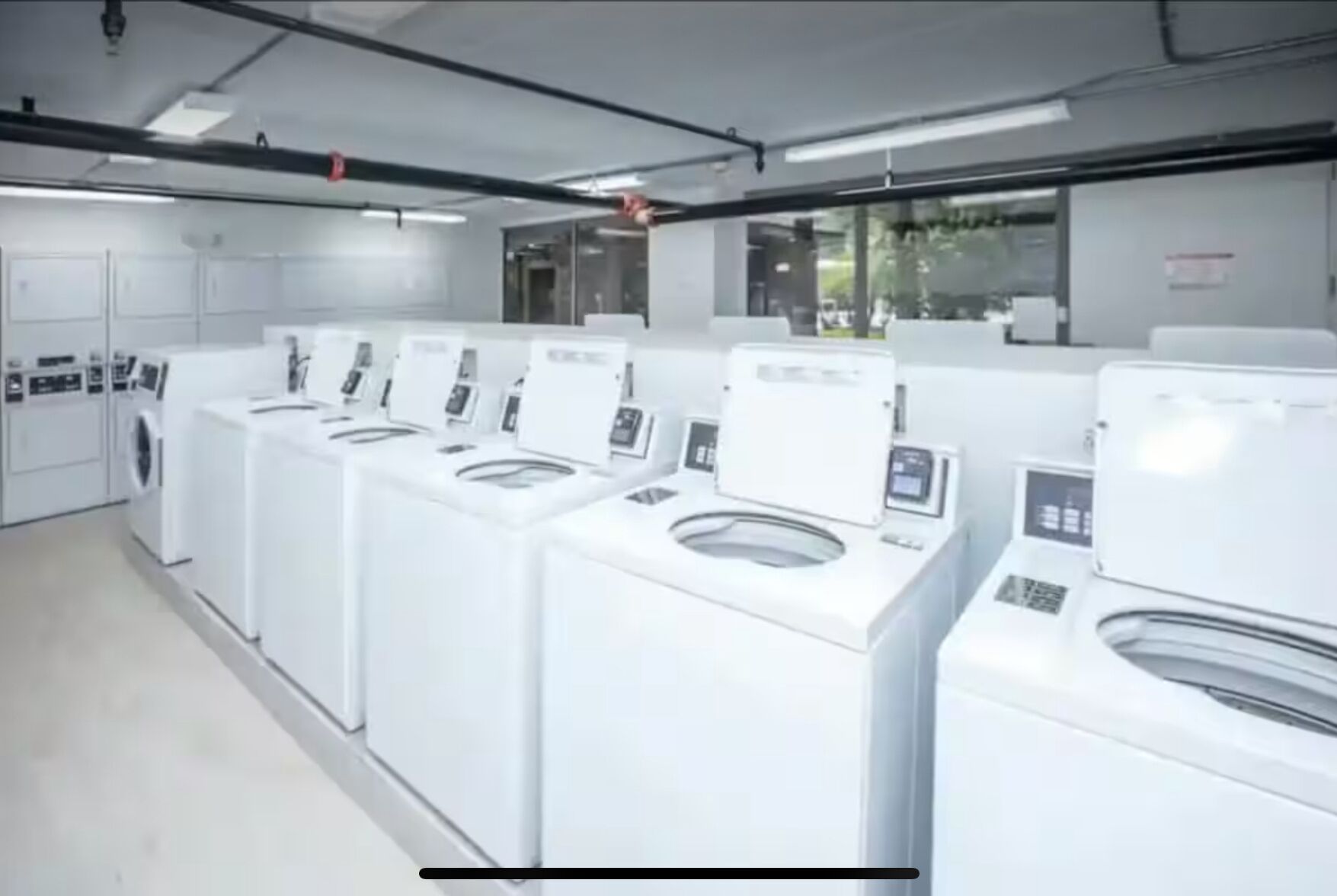 A row of white laundry machines in a clean, modern laundry facility.