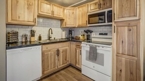 A kitchen with wooden cabinets, a stainless steel sink, a microwave, and a stove.