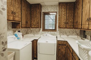 Una cocina compacta con armarios de madera, una ventana y una lavadora.
