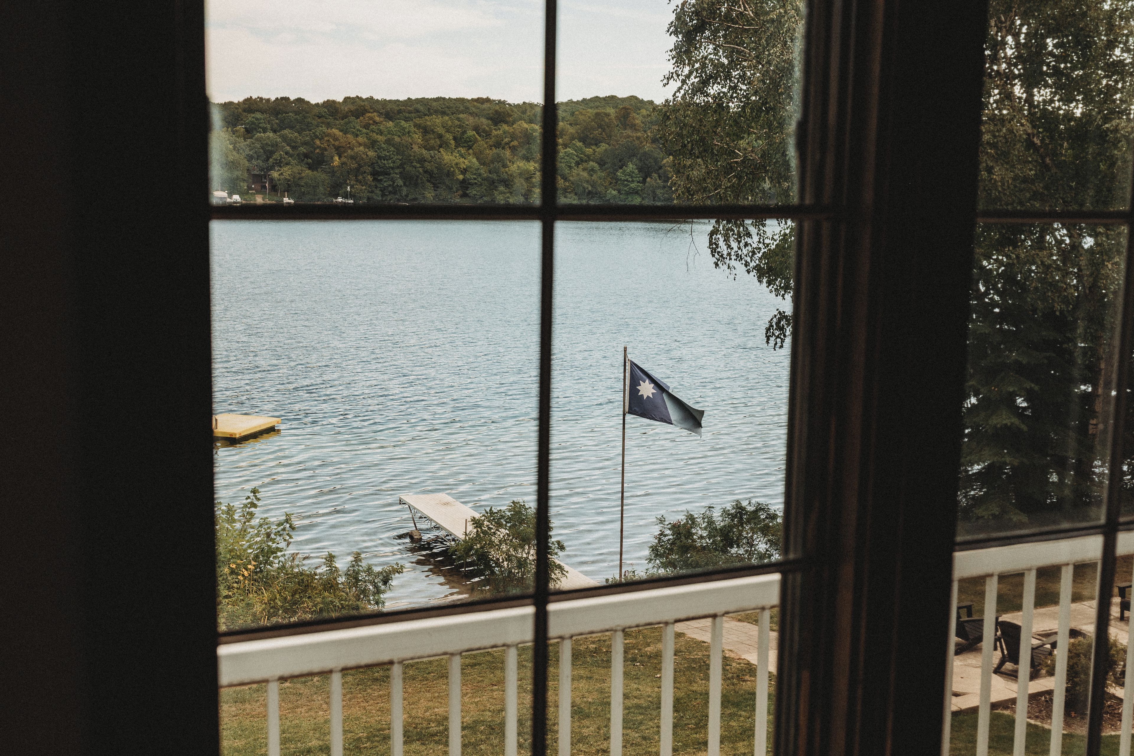 Une vue sur un lac, prise depuis une fenêtre, avec un drapeau flottant sur un quai.