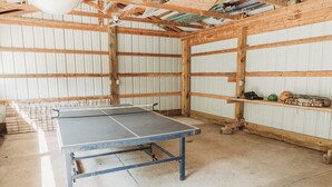 Ein Tischtennis-Tisch in einem Raum mit Holzbalken und wellenförmigem Metall.