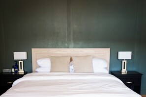 Una habitación de hotel con una cama grande, dos mesitas de noche y un reloj de pared.