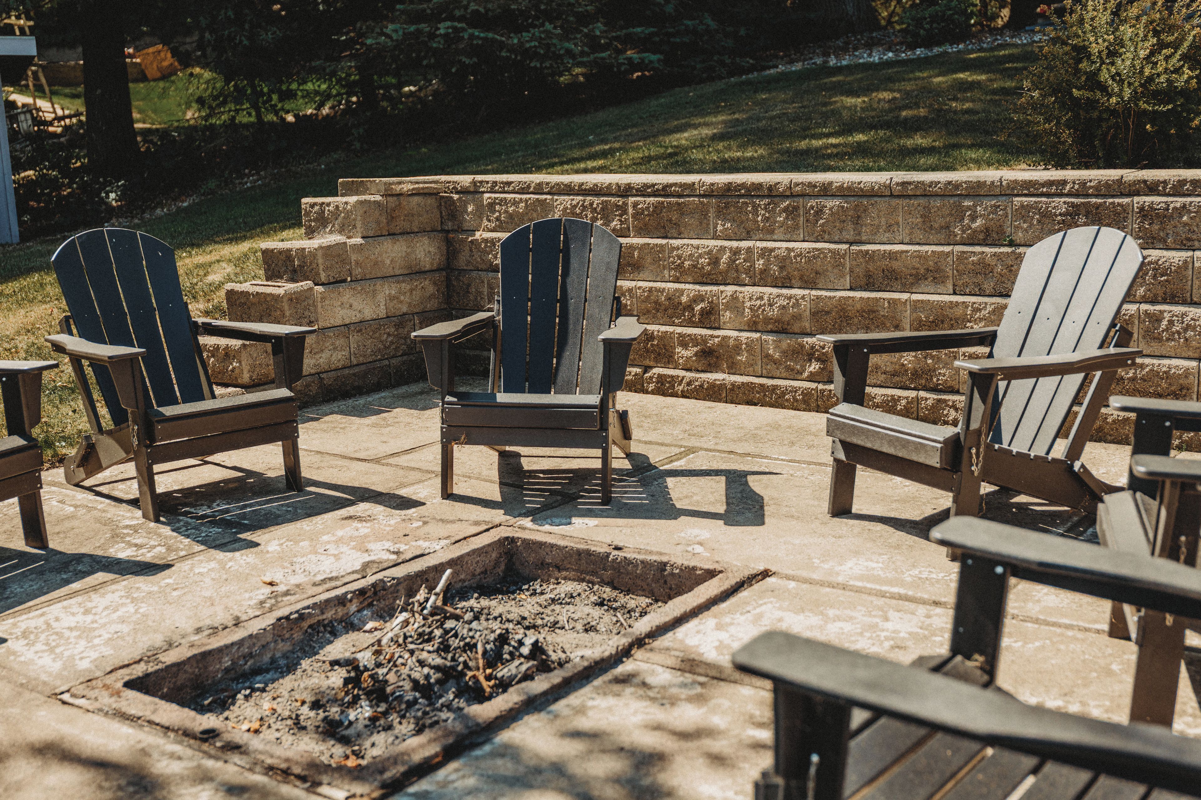 Un espace extérieur aménagé avec des chaises Adirondack et un foyer.