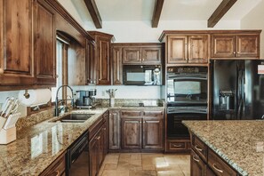 Una cocina con armarios de madera, encimeras de granito y electrodomésticos de acero inoxidable, incluyendo un horno empotrado.