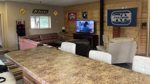 Una sala de estar con encimera de granito, sofás de cuero, un televisor y una pared de madera con un cartel de aniversario Polaris.