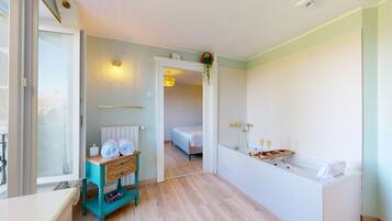 Une chambre d’hôtel comprenant un lit, une petite table avec des serviettes, une table de chevet, une lampe fixée au mur et un espace douche.