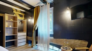 A modern room with a wooden floor, a bed, a seating area with a table, a wardrobe, and a large window with curtains. - House with Spa and Private Sauna (Lissac-sur-Couze)