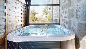 A hot tub with two glasses of champagne, a wooden wall, and a stone wall with a window. - House with Spa and Private Sauna (Lissac-sur-Couze)