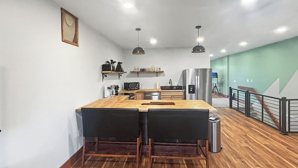 Une cuisine moderne dotée de plans de travail en bois, d’un réfrigérateur en acier inoxydable et d’un coin repas avec deux chaises.