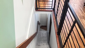 Un escalier avec une main courante en bois et une rampe en métal noir, menant à l’étage supérieur.