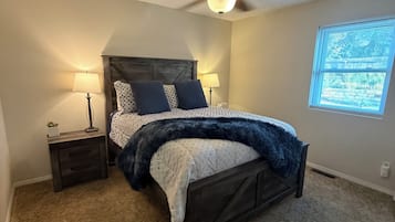 Una camera da letto con un letto, comodini, una ventola a soffitto e una finestra.