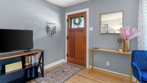 A living room with a TV, console table, and blue chair. - The Yellow Haus, close to downtown Waterloo! (Waterloo)